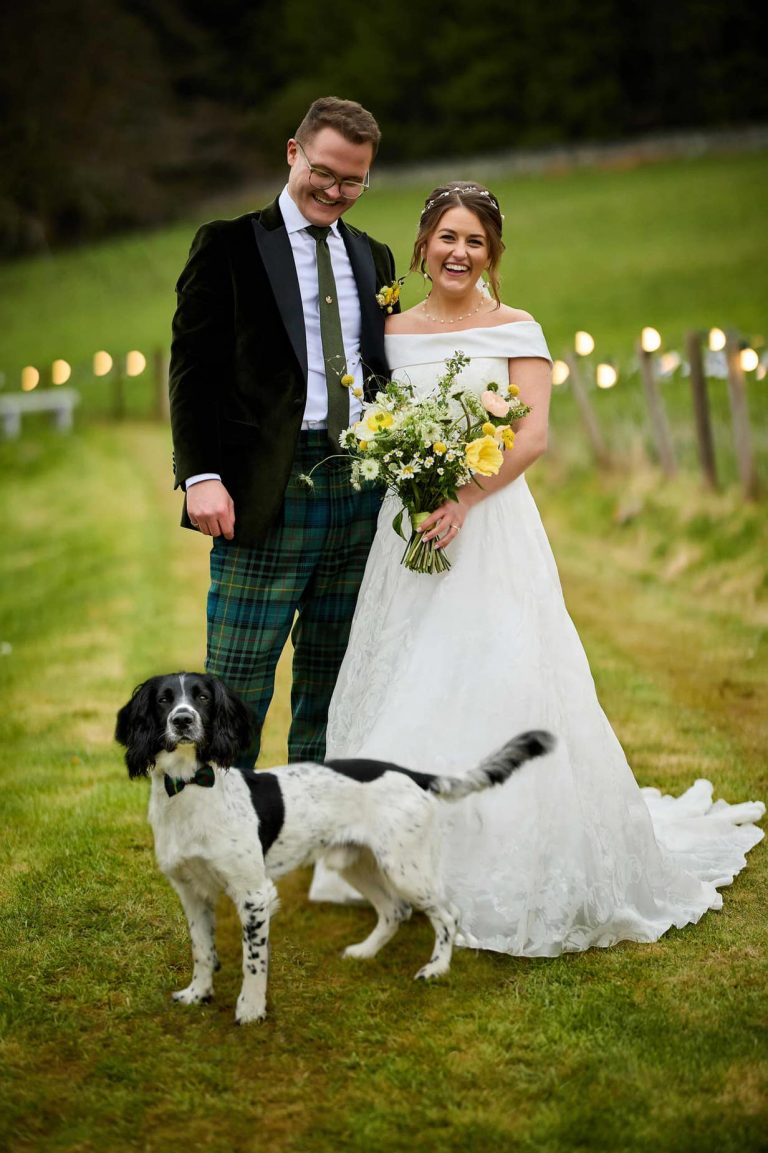 Couple and their dog, in a field on wedding day