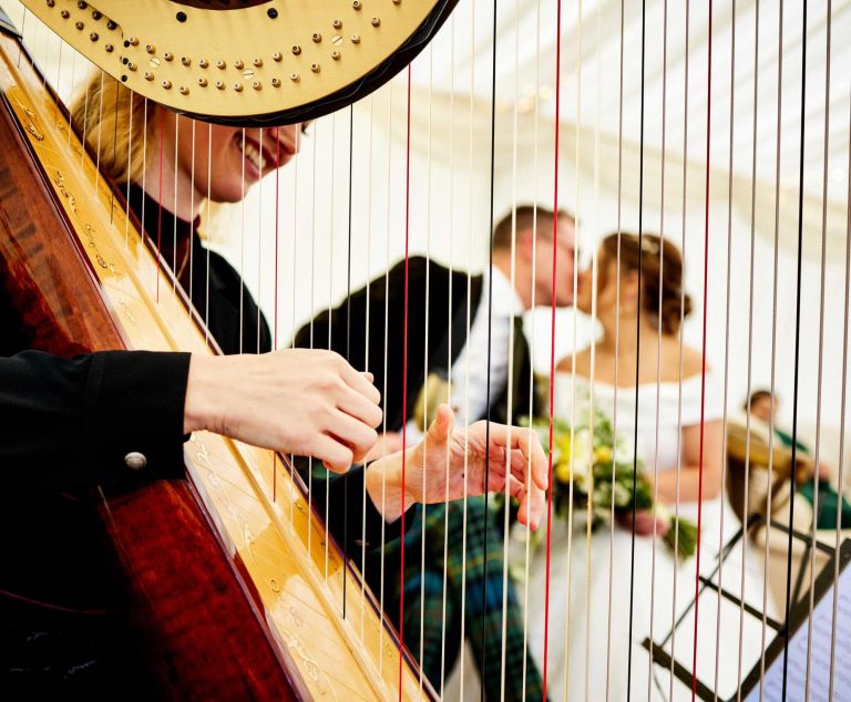 Wedding couple kissing with the harp in the background through the harp