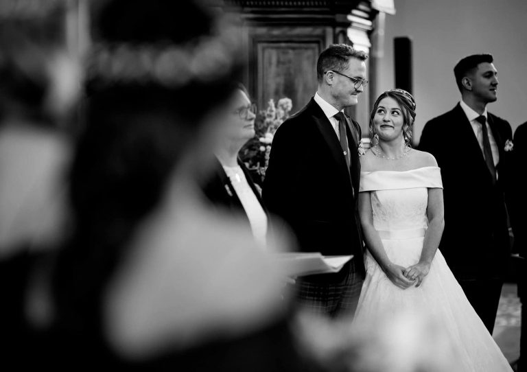 Bridal Couple sneaking a look at each other at the ceremony in black and white
