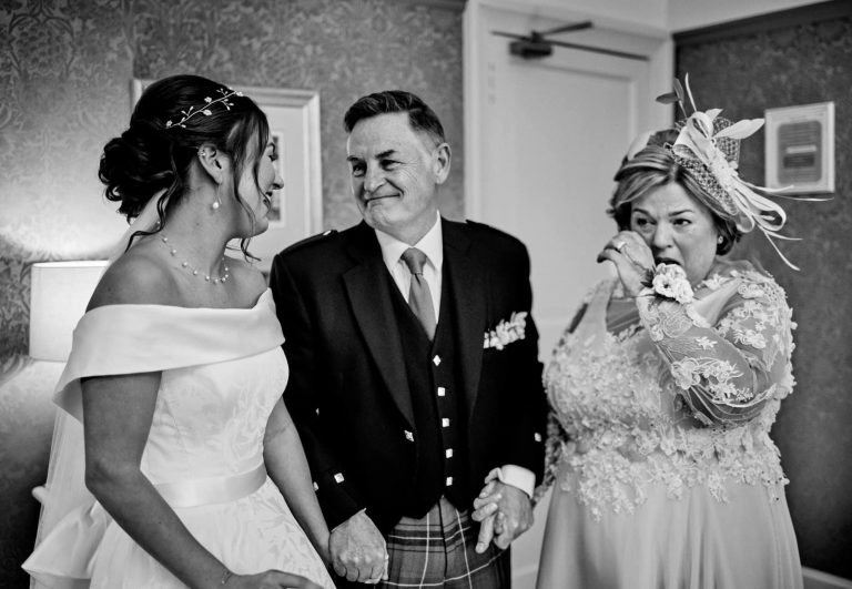 Bride and parents looking at each other. Mother of the bride in tears. In black and white
