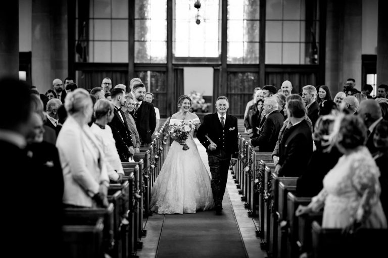 Bridal couple walking down the Isle of church in black and white